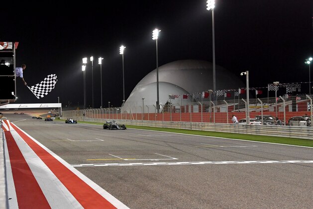 Former British football player David Beckham (L) waves the checkered flag as Mercedes' British driver Lewis Hamilton crosses the finish line during the Formula One Bahrain Grand Prix at the Sakhir circuit in the desert south of the Bahraini capital Manama, on March 31, 2019. (Photo by Andrej ISAKOVIC / various sources / AFP)        (Photo credit should read ANDREJ ISAKOVIC/AFP via Getty Images)