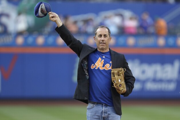 Comedian Jerry Seinfeld gestures to fans before throwing out a ceremonial first pitch before a baseball game between the New York Mets and the Philadelphia Phillies on Friday, July 5, 2019, in New York. (AP Photo/Frank Franklin II)