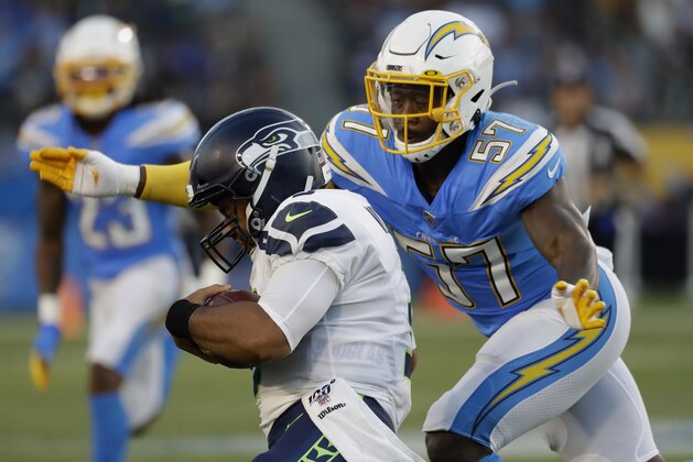 Seattle Seahawks quarterback Russell Wilson (3) gets stopped by Los Angeles Chargers outside linebacker Jatavis Brown (57) in pursuit during the first half of an NFL preseason football game in Carson, Sunday, Aug. 25, 2019. (AP Photo/Alex Gallardo)