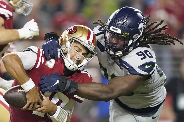 San Francisco 49ers quarterback Jimmy Garoppolo, left, avoids being sacked by Seattle Seahawks defensive end Jadeveon Clowney (90) during the second half of an NFL football game in Santa Clara, Calif., Monday, Nov. 11, 2019. (AP Photo/Tony Avelar)