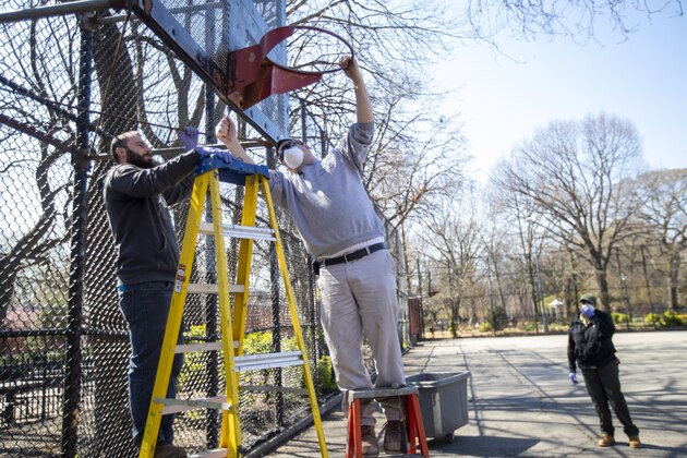 New York City Department of Parks and Recreation employees remove the basketball hoop from a court in Tompkins Square Park, Thursday, March 26, 2020, in New York. New York City Mayor Bill de Blasio said authorities would remove basketball hoops at 80 public courts where people were not respecting coronavirus social-distancing instructions not to shoot around with anyone outside their households, while leaving up roughly 1,700 others where there were no problems. The new coronavirus causes mild or moderate symptoms for most people, but for some, especially older adults and people with existing health problems, it can cause more severe illness or death. (AP Photo/Mary Altaffer) New York City Department of Parks and Recreation employees remove the basketball hoop from a court in Tompkins Square Park, Thursday, March 26, 2020, in New York. New York City Mayor Bill de Blasio said authorities would remove basketball hoops at 80 public courts where people were not respecting coronavirus social-distancing instructions not to shoot around with anyone outside their households, while leaving up roughly 1,700 others where there were no problems. The new coronavirus causes mild or moderate symptoms for most people, but for some, especially older adults and people with existing health problems, it can cause more severe illness or death. (AP Photo/Mary Altaffer)