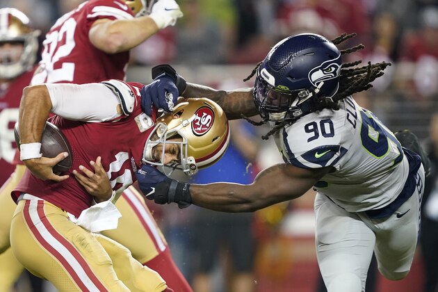San Francisco 49ers quarterback Jimmy Garoppolo, left, avoids being sacked by Seattle Seahawks defensive end Jadeveon Clowney (90) during the second half of an NFL football game in Santa Clara, Calif., Monday, Nov. 11, 2019. (AP Photo/Tony Avelar)