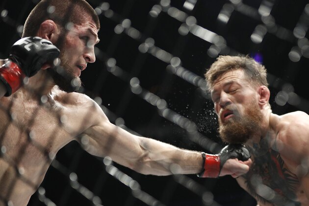 FILE - In this Oct. 6, 2018, file photo, Khabib Nurmagomedov, left, punches Conor McGregor during a lightweight title mixed martial arts bout at UFC 229 in Las Vegas. Nurmagomedov has not fought in the 11 months since he punctuated his star-making victory over McGregor at UFC 229 in Las Vegas by scaling the fence and jumping into the crowd to fight McGregor’s entourage. (AP Photo/John Locher, File)