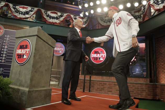 Major League Baseball commissioner Rob Manfred, left, greets Jackson Rutledge, a right handed pitcher from San Jacinto Junior College, in Pasadena, Tex., after he was selected No. 17 by the Washington Nationals in the first round of the Major League Baseball draft, Monday, June 3, 2019, in Secaucus, N.J. (AP Photo/Julio Cortez)