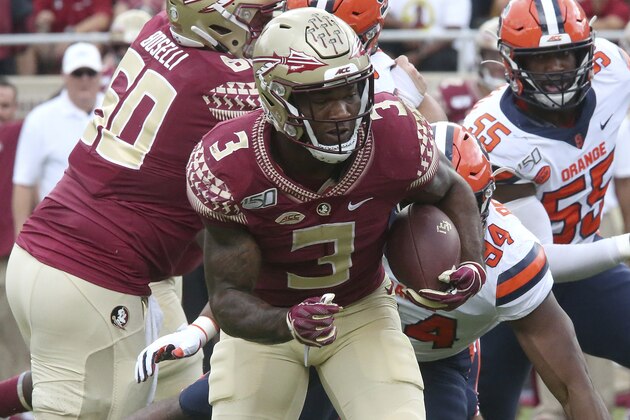 Florida State's Cam Akers, left, runs against Syracuse defense during an NCAA college football game, Saturday, Oct. 26, 2019 in Tallahassee Fla. Florida State won 35-17. (AP Photo/Steve Cannon)