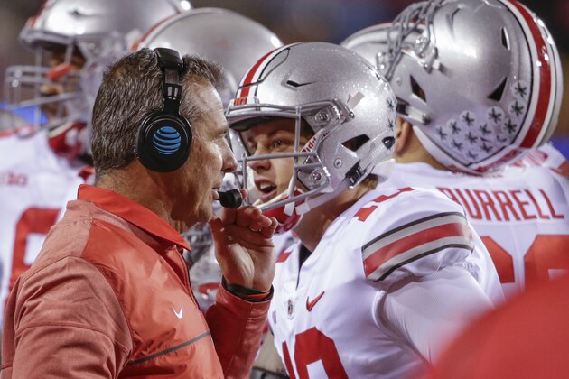 Ohio State head coach Urban Meyer talks to on his headset as quarterback Joe Burrow (10) talks to a different person, during a time out in the second half of an NCAA college football game against Nebraska in Lincoln, Neb., Saturday, Oct. 14, 2017. Ohio State won 56-14. (AP Photo/Nati Harnik)