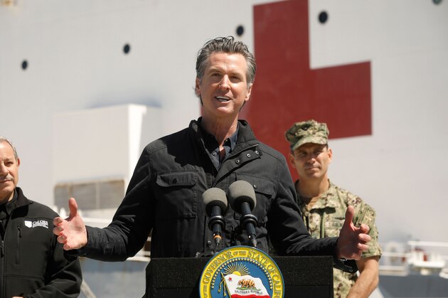 California Governor Gavin Newsom (C), flanked by Director Mark Ghilarducci, Cal OES, (L) and Admiral John Gumbleton, United States Navy, speaks in front of the hospital ship USNS Mercy after it arrived into the Port of Los Angeles on March 27, 2020. - The USNS Mercy, a giant US naval hospital ship, arrived in Los Angeles on March 27, where it will be used to ease the strain on the city's coronavirus-swamped emergency rooms. (Photo by Carolyn Cole / POOL / AFP) (Photo by CAROLYN COLE/POOL/AFP via Getty Images)