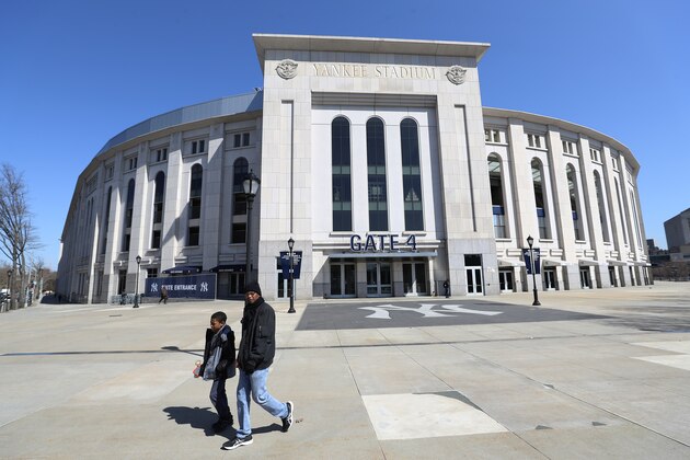 BRONX, NEW YORK - MARCH 26:  A father and son walk past a closed Yankee Stadium on the scheduled date for Opening Day March 26, 2020 in the Bronx, New York. Major League Baseball has postponed the start of its season due to the coronavirus (COVID-19) outbreak and MLB commissioner Rob Manfred recently said the league is