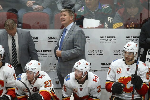 Calgary Flames head coach Bill Peters, middle, looks up at the scoreboard during the third period of an NHL hockey game against the Arizona Coyotes as Flames' Johnny Gaudreau (13), center Sean Monahan (23), Elias Lindholm (28) and Michael Frolik (67) watch the action on the ice, Saturday, Nov. 16, 2019, in Glendale, Ariz. The Coyotes defeated the Flames 3-0. (AP Photo/Ross D. Franklin)