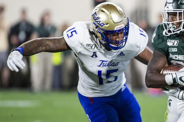 Tulsa defensive end Trevis Gipson (15) attempts a tackle on Michigan State running back Elijah Collins (24) during the second half of an NCAA football game on Friday, Aug. 30, 2019 in East Lansing, Mich. Michigan State won 28-7. (AP Photo/Tony Ding)