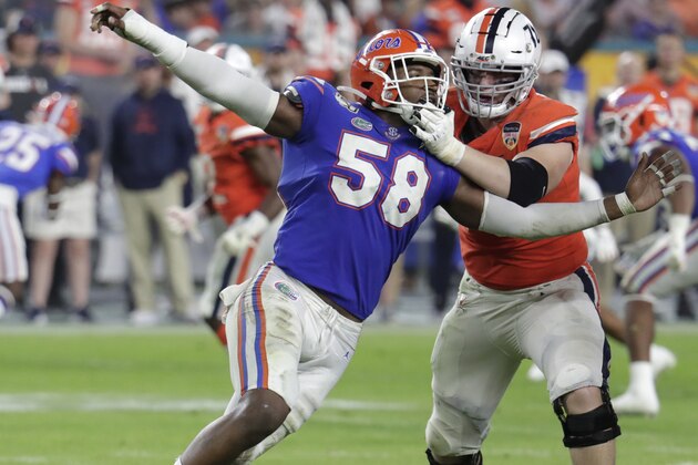 Virginia offensive tackle Bobby Haskins, right, defends Florida linebacker Jonathan Greenard (58) during the second half of the Orange Bowl NCAA college football game between Florida and Virginia, Monday, Dec. 30, 2019, in Miami Gardens, Fla. (AP Photo/Lynne Sladky)