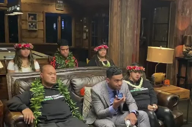 In this still image from video provided by the NFL, Tua Tagovailoa, front center, holds up a phone during the NFL football draft Thursday, April 23, 2020. The Miami Dolphins selected Tagovailoa with the fifth pick. (NFL via AP)