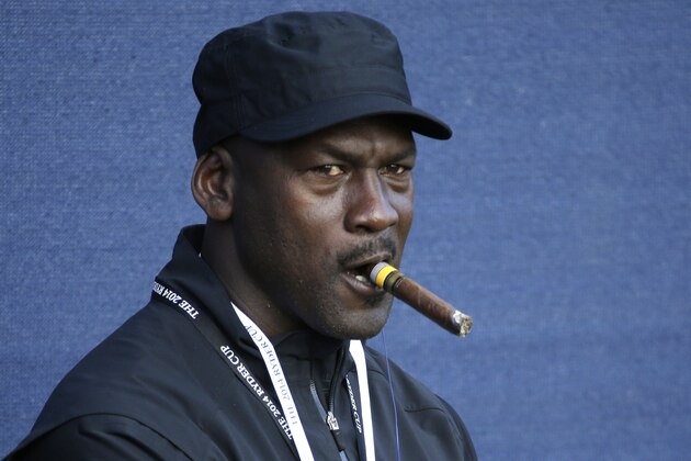 Basketball legend Michael Jordan smokes a cigar while watching the fourball match on the first day of the Ryder Cup golf tournament, at Gleneagles, Scotland, Friday, Sept. 26, 2014. (AP Photo/Matt Dunham)