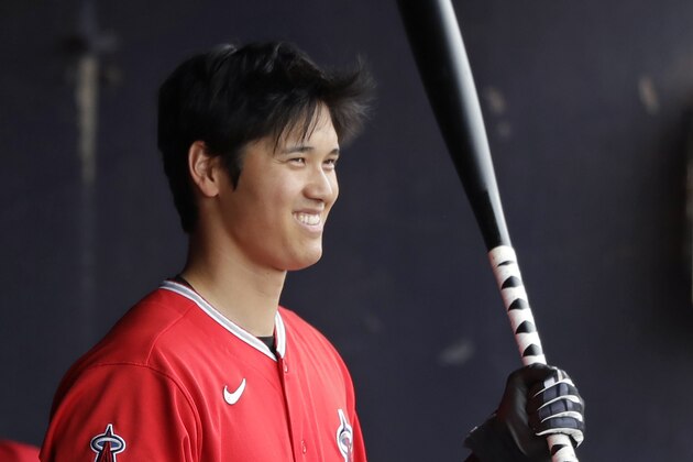 Los Angeles Angels' Shohei Ohtani smiles as he looks out from the dugout before his turn to bat against the Seattle Mariners during a spring training baseball game Tuesday, March 10, 2020, in Peoria, Ariz. (AP Photo/Elaine Thompson)