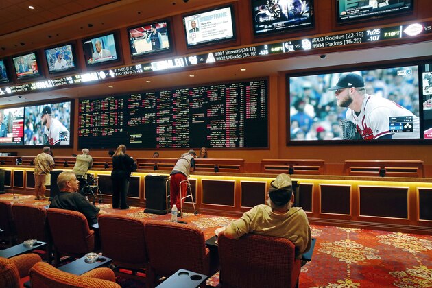 FILE - In this Monday, May 14, 2018, file photo, people make bets in the sports book at the South Point hotel and casino in Las Vegas. Nevada regulators have rejected a request from Major League Baseball to ban betting on spring training games. The Nevada Gaming Control Board says the state has the proper controls in place to minimize the league's integrity concerns. (AP Photo/John Locher, File)