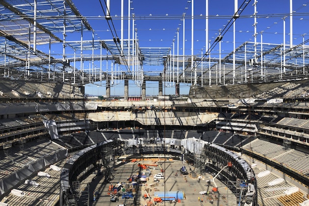 An airplane flies past as construction continues at SoFi Stadium on Wednesday, Feb. 26, 2020, in Inglewood, Calif. The leaders of the Pac-12 and Mountain West conferences formally announced the new LA Bowl on Wednesday at the under-construction stadium south of downtown Los Angeles. For at least the next six years, the Mountain West's top team will face the fifth choice from the Pac-12 in December in the home stadium of the NFL's Rams and Chargers. (AP Photo/Greg Beacham)