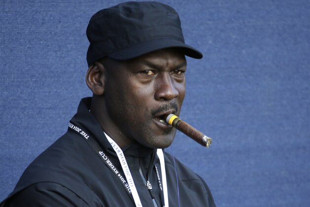 Basketball legend Michael Jordan smokes a cigar while watching the fourball match on the first day of the Ryder Cup golf tournament, at Gleneagles, Scotland, Friday, Sept. 26, 2014. (AP Photo/Matt Dunham)