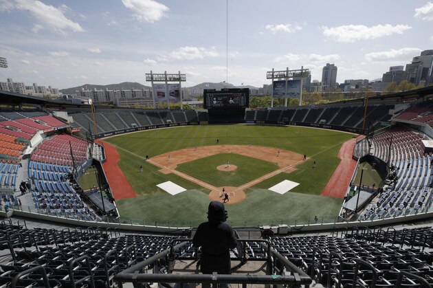 A TV cameraman films in the empty stadium as a part of precaution against the new coronavirus during the pre-season baseball game between Doosan Bears and LG Twins in Seoul, South Korea, Tuesday, April 21, 2020. South Korea's professional baseball league has decided to begin its new season on May 5, initially without fans, following a postponement over the coronavirus. (AP Photo/Lee Jin-man)