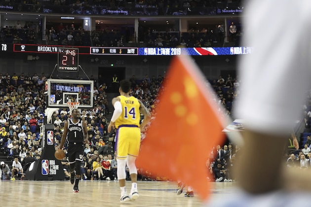 In this Thursday, Oct. 10, 2019, photo, Brooklyn Nets' Theo Pinson, left, drives against Los Angeles Lakers' Danny Green, right, near a Chinese national flag during a preseason NBA game at the Mercedes Benz Arena in Shanghai, China. When Houston Rocket's general manager Daryl Morey tweeted last week in support of anti-government protests in Hong Kong, everything changed for NBA fans in China. A new chant flooded Chinese sports forums: