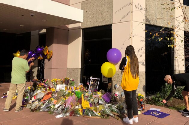 Wearing a Kobe Bryant No. 8 Lakers jersey, Olivia Tyler, 19, of Simi Valley, Calif., and others view the memorial at the Mamba Sports Academy in Thousand Oaks, Calif., and pray for the families of the victims of the Sunday helicopter crash that took the lives of the former Lakers star and eight others, Monday morning, Jan. 27, 2020. Tyler said she has idolized Bryant for years and that she previously played at the sports academy but before Bryant bought it. She met him at a UCLA basketball game in 2017 and he gave her a high-five.