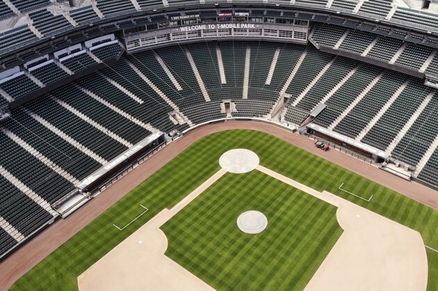 In an otherwise empty ballpark, grounds crew members continue to keep the Seattle Mariners' field in playing shape as the ballpark goes into its seventh week without baseball played because of the coronavirus outbreak, Monday, May 11, 2020, in Seattle. A person familiar with the decision tells The Associated Press that Major League Baseball owners have given the go-ahead to making a proposal to the players' union that could lead to the coronavirus-delayed season starting around the Fourth of July weekend in ballparks without fans. (AP Photo/Elaine Thompson)