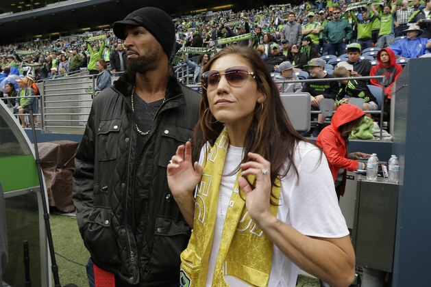 Hope Solo, right, goalkeeper for the United States women's national soccer team and the Seattle Reign FC, stands with her husband, former NFL football player Jerramy Stevens, left, on the sideline before an MLS soccer match between the Seattle Sounders and the Portland Timbers, Sunday, Aug. 30, 2015, in Seattle. (AP Photo/Ted S. Warren)