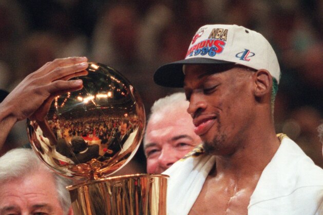 FILE - This June 16, 1996, file photo shows Chicago Bulls' Dennis Rodman admiring the Larry O'Brien NBA Championship trophy after the Bulls defeated the Seattle SuperSonics 87-75 to clinch the 1996 NBA title, in Chicago. Beyond the outrageous outfits and tabloid tales,  Rodman was also a five-time NBA champion who won 70 percent of his games.  He gets recognition for his basketball achievements FridayAug. 12, 2011,  when he joins Dream Teamer Chris Mullin as the headline names in the 2011 Naismith Memorial Hall of Fame class. (AP Photo/Beth A. Keiser, File)
