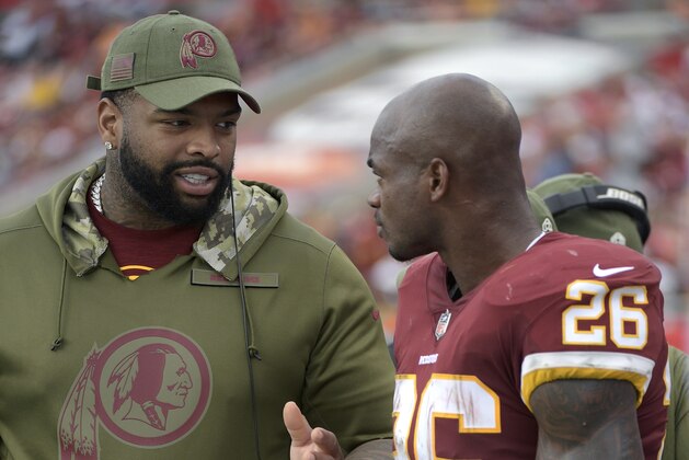 Washington Redskins offensive tackle Trent Williams, left, talks with running back Adrian Peterson (26) on the sideline during the second half of an NFL football game against the Tampa Bay Buccaneers Sunday, Nov. 11, 2018, in Tampa, Fla. (AP Photo/Phelan M. Ebenhack)
