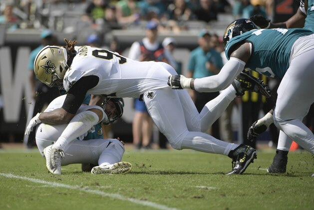 Jacksonville Jaguars quarterback Gardner Minshew, lower left, is sacked by New Orleans Saints defensive end Cameron Jordan, center, as Jaguars offensive tackle Jawaan Taylor, right, tries to slow Jordan down during the first half of an NFL football game, Sunday, Oct. 13, 2019, in Jacksonville, Fla. (AP Photo/Phelan M. Ebenhack)