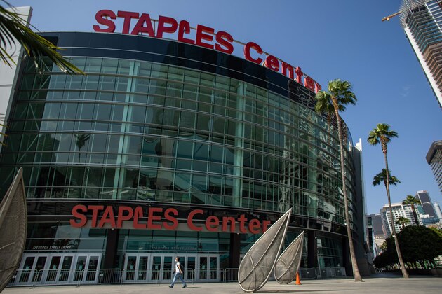A man wearing a face mask walks in front of the Staples Center in downtown Los Angeles, California, on May 9, 2020, during the novel coronavirus pandemic. - Events that involve mass gatherings, like sporting events and concerts, are unlikely to reopen until the threat of the novel coronavirus has largely passed. (Photo by Apu GOMES / AFP) (Photo by APU GOMES/AFP via Getty Images)