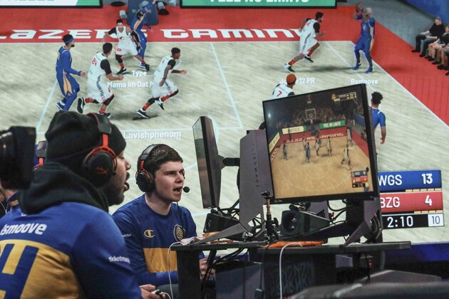 A giant monitor shows play as Warriors Gaming Squad teammates Charles