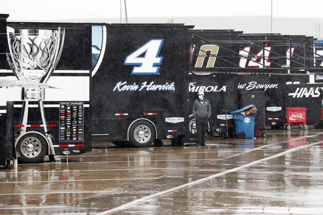 A man watches as rain falls in the infield before a NASCAR Cup Series auto race at Charlotte Motor Speedway Wednesday, May 27, 2020, in Concord, N.C. (AP Photo/Gerry Broome)