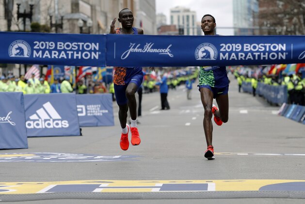 FILE - In this April 15, 2019, file photo, Lawrence Cherono, left, of Kenya, runs to the finish line to win the 123rd Boston Marathon in front of Lelisa Desisa, of Ethiopia, right, in Boston. The Boston Marathon is offering refunds for the first time because of the new coronavirus pandemic. Race organizers say anyone who was entered in the 124th edition of the race this month can still run on the rescheduled date, Sept. 14. But if they canâ€™t make it, they can have their money back. (AP Photo/Winslow Townson, File)