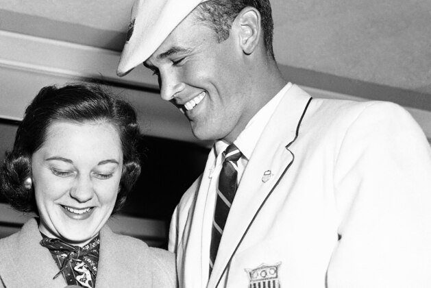 FILE - In this Dec. 8, 1956, file photo, Bobby Joe Morrow, right, the spirit champion of the just-concluded Olympic Games in Melbourne, Australia, shows one of his three gold medals to his wife, Joann, upon his arrival by air in Los Angeles. Morrow, the Texas sprinter who won three gold medals in the 1956 Melbourne Olympics while a student at Abilene Christian University, died Saturday, May 30, 2020. He was 84. (AP Photo/HF, File)