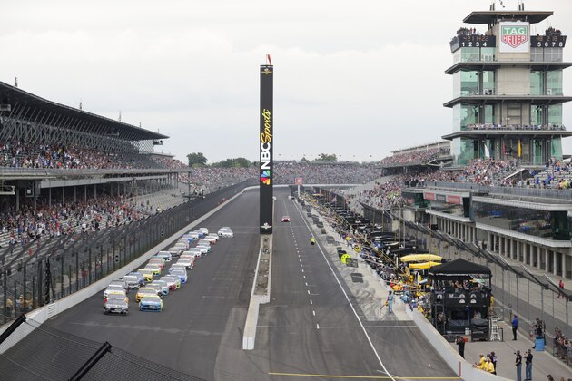 FILE - In this Sept. 8, 2019, file photo, Kevin Harvick, left, and Paul Menard lead the field into the first turn on the start of the NASCAR Brickyard 400 auto race at Indianapolis Motor Speedway, in Indianapolis. Indianapolis Motor Speedway and the IndyCar Series have been sold to Penske Entertainment Corp. in a stunning announcement that relinquishes control of the iconic speedway from the Hulman family after 74 years. (AP Photo/Michael Conroy, File)