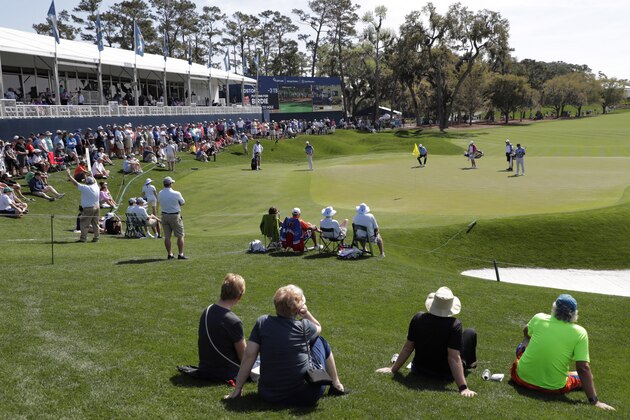 A sparse crowd sits around the 18th green, during the first round of The Players Championship golf tournament Thursday, March 12, 2020 in Ponte Vedra Beach, Fla. The PGA Tour announced that The Players Championship golf tournament will proceed without fans. The policy will start on Friday and will continue through the Valero Texas Open. (AP Photo/Lynne Sladky) A sparse crowd sits around the 18th green, during the first round of The Players Championship golf tournament Thursday, March 12, 2020 in Ponte Vedra Beach, Fla. The PGA Tour announced that The Players Championship golf tournament will proceed without fans. The policy will start on Friday and will continue through the Valero Texas Open. (AP Photo/Lynne Sladky)