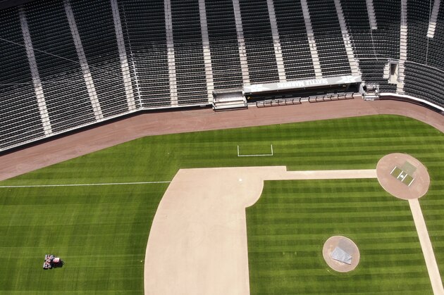 A grounds crew member mows in right field as work continues to keep the Seattle Mariners' field in playing shape as the ballpark goes into its seventh week without baseball played because of the coronavirus outbreak, Monday, May 11, 2020, in Seattle. A person familiar with the decision tells The Associated Press that Major League Baseball owners have given the go-ahead to making a proposal to the players' union that could lead to the coronavirus-delayed season starting around the Fourth of July weekend in ballparks without fans. (AP Photo/Elaine Thompson)