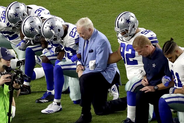 FILE - In this Monday, Sept. 25, 2017, file photo, the Dallas Cowboys, led by owner Jerry Jones, center, take a knee prior to the national anthem before an NFL football game against the Arizona Cardinals in Glendale, Ariz. What began more than a year ago with a lone NFL quarterback protesting police brutality against minorities by kneeling silently during the national anthem before games has grown into a roar with hundreds of players sitting, kneeling, locking arms or remaining in locker rooms, their reasons for demonstrating as varied as their methods. (AP Photo/Matt York, File)
