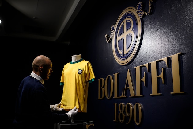 A staff member displays a jersey of Brazilian football legend Pele, during a preview of Sport Memorabilia items, at the Bolaffi auction house in Turin, on November 27, 2019. - Online auction of sports memorabilia will be held on December 5, 2019. (Photo by Marco BERTORELLO / AFP) (Photo by MARCO BERTORELLO/AFP via Getty Images)