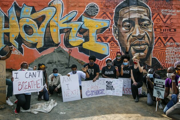 Protesters against police violence gather next to a new mural painted this week showing George Floyd with the Swahili word