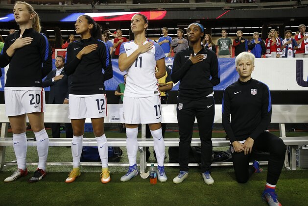 USA's Megan Rapinoe, right, kneels next to teammates Samanth Mewis (20) Christen Press (12), Ali Krieger (11), Crystal Dunn (16) and Ashlyn Harris (22) as the US national anthem is played before an exhibition soccer match against Netherlands Sunday, Sept. 18, 2016, in Atlanta.  (AP Photo/John Bazemore)