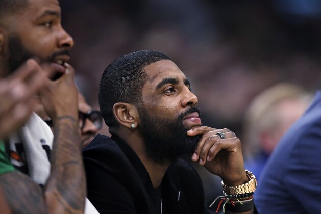 Boston Celtics guard Kyrie Irving, center, who is sidelined with a hip strain, watches play from the bench with forward Marcus Morris, left, during the first quarter of the team's NBA basketball game against the Charlotte Hornets in Boston, Wednesday, Jan. 30, 2019. (AP Photo/Charles Krupa)