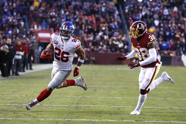 New York Giants running back Saquon Barkley (26) runs with the ball as Washington Redskins defensive back Kayvon Webster (38) chases him during overtime of an NFL football game, Sunday, Dec. 22, 2019, in Landover, Md. The Giants won 41-35 in overtime. (AP Photo/Patrick Semansky)