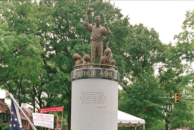 FILE - In this July 10, 1996 file photo, a crowd gathers at the base of the Arthur Ashe Monument after the ceremony dedicating the statue on Monument Avenue in Richmond, Va. The statue of the African American tennis legend has been vandalized with the words “White Lives Matter.” Richmond Police said they were alerted to the vandalism Wednesday, June 17, 2020. Police say red paint on the statue itself was already being cleaned off by community members. (AP Photo/Steve Helber) FILE - In this July 10, 1996 file photo, a crowd gathers at the base of the Arthur Ashe Monument after the ceremony dedicating the statue on Monument Avenue in Richmond, Va. The statue of the African American tennis legend has been vandalized with the words “White Lives Matter.” Richmond Police said they were alerted to the vandalism Wednesday, June 17, 2020. Police say red paint on the statue itself was already being cleaned off by community members. (AP Photo/Steve Helber)