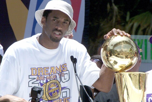 Kobe Bryant puts his hand on the NBA championship trophy at the end of the Los Angeles Lakers victory parade through downtown  Los Angeles 21 June 2000.  About 200,000 fans lined the streets to cheer on the Lakers  NBA 2000 championship.  (ELECTRONIC IMAGE)  AFP PHOTO/VINCE BUCCI (Photo by VINCE BUCCI / AFP) (Photo by VINCE BUCCI/AFP via Getty Images)