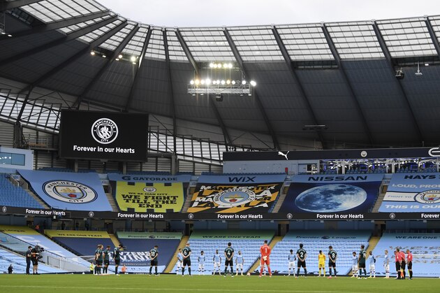 Players and match officials stand in a minutes silence for the victims of the coronavirus disease ahead of the English Premier League soccer match between Manchester City and Burnley at Etihad Stadium, in Manchester, England, Monday, June 22, 2020. (AP Photo/Shaun Botterill,Pool)