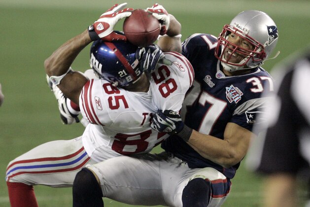 New York Giants receiver David Tyree (85) holds on by his fingertips to a 32-yard pass as New England Patriots safety Rodney Harrison (37) pulls him down after the catch during the fourth quarter of the Super Bowl football game Sunday, Feb. 3, 2008 in Glendale, Ariz. Somehow, with time running out and the ball pinned to his helmet, Tyree held on tight with both hands Sunday. Years from now, New York Giants fans will still wonder how he did it. The Giants won 17-14. (AP Photo/Elaine Thompson)