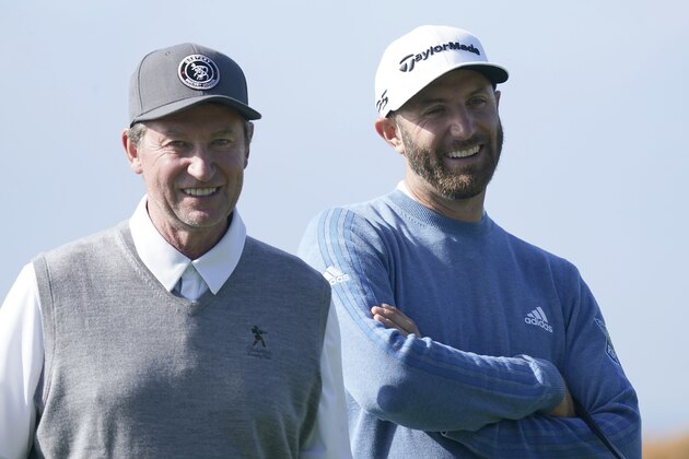Wayne Gretzky, left, and Dustin Johnson wait on the sixth green of the Monterey Peninsula County Club Shore Course during the second round of the AT&T Pebble Beach National Pro-Am golf tournament Friday, Feb. 7, 2020, in Pebble Beach, Calif. (AP Photo/Tony Avelar)