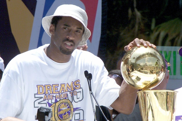 Kobe Bryant puts his hand on the NBA championship trophy at the end of the Los Angeles Lakers victory parade through downtown  Los Angeles 21 June 2000.  About 200,000 fans lined the streets to cheer on the Lakers  NBA 2000 championship.  (ELECTRONIC IMAGE)  AFP PHOTO/VINCE BUCCI (Photo by VINCE BUCCI / AFP) (Photo by VINCE BUCCI/AFP via Getty Images)