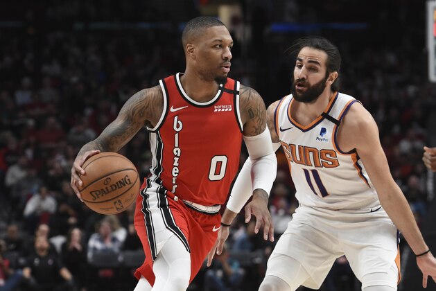 Portland Trail Blazers guard Damian Lillard, left, dribbles the ball past Phoenix Suns guard Ricky Rubio, right, during the first quarter of an NBA basketball game in Portland, Ore., Tuesday, March 10, 2020. (AP Photo/Steve Dykes)